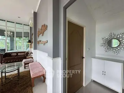 Charming living room with elegant decor and large windows offering lush garden views.