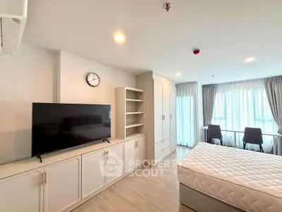 Spacious modern bedroom with large TV and natural light in a stylish apartment.