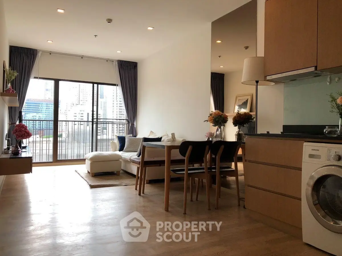 Spacious modern living room with open kitchen and city view balcony in luxury apartment.