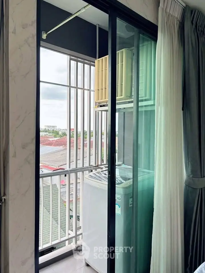 Compact balcony with washing machine and city view, ideal for urban living convenience.