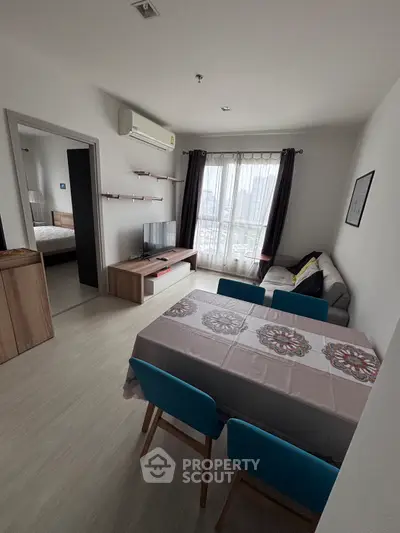 Modern living room with dining area, featuring stylish furniture and natural light from large windows.