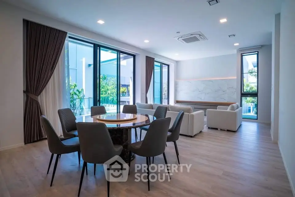 Spacious modern living room with elegant dining area and large windows offering natural light.