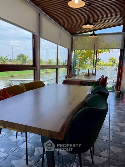 Charming sunlit dining area with large windows and garden view, perfect for gatherings.