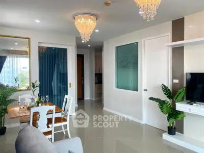 Elegant living room with modern decor and dining area, featuring chandeliers and large mirror.