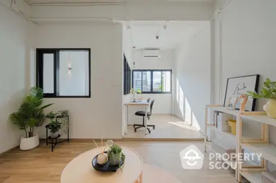 Bright and airy modern living space with minimalist decor, large windows, and sleek white walls complemented by warm wooden flooring.