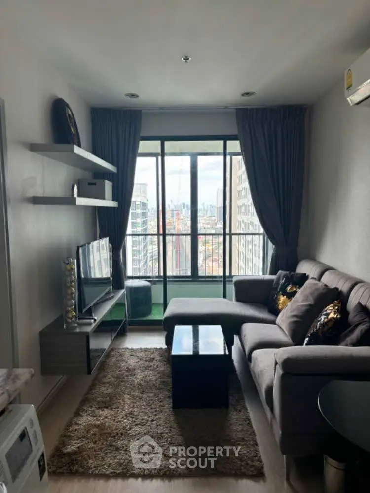 Modern living room with city view, cozy sofa, and stylish decor in high-rise apartment.