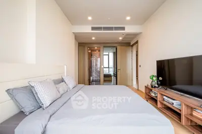 Spacious modern bedroom with elegant decor and large TV, perfect for relaxation.