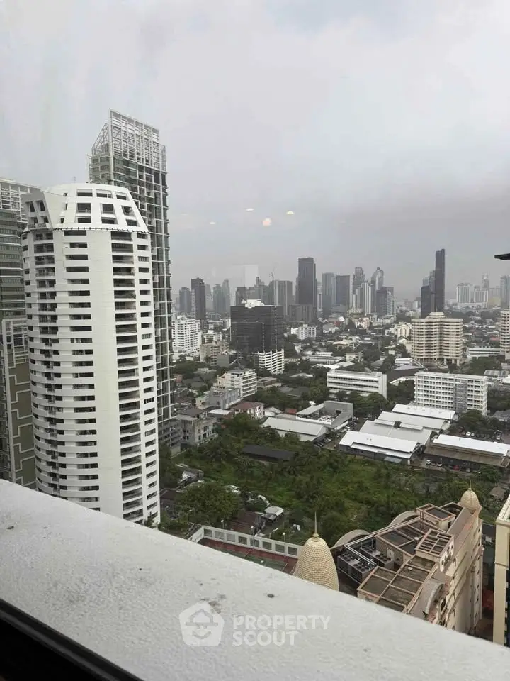 Stunning cityscape view from high-rise building showcasing urban skyline and lush greenery.