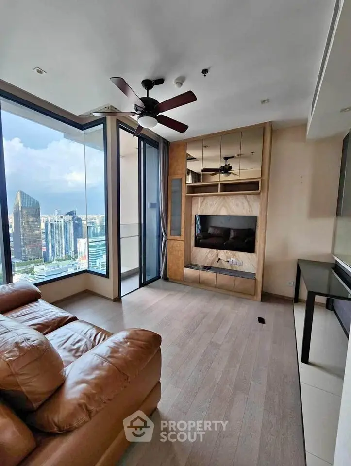 Modern living room with city view, featuring leather sofa and ceiling fan