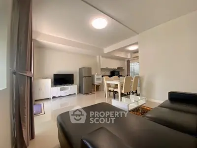 Spacious open-plan living room with modern furnishings and kitchen area, perfect for entertaining.