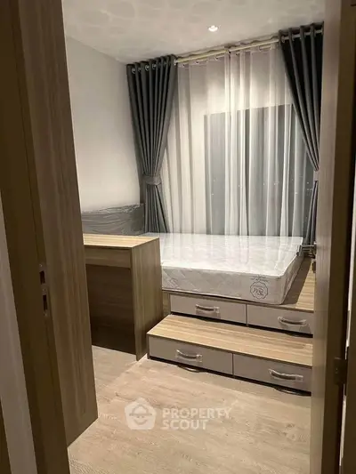 Cozy bedroom with modern design, featuring a bed with storage drawers and elegant curtains.