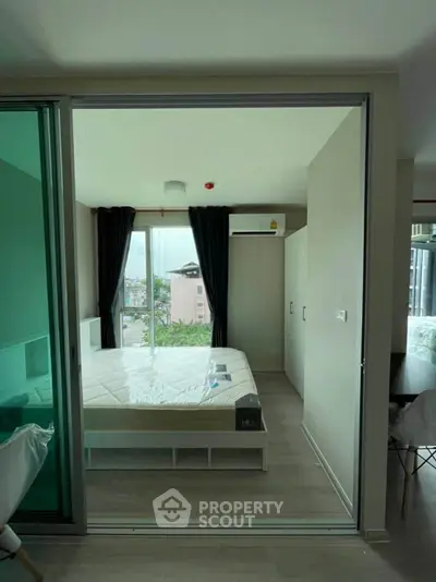 Modern bedroom with large window and city view, featuring sleek design and ample natural light.