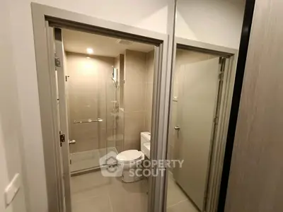 Modern bathroom with glass shower and sleek fixtures in contemporary apartment.