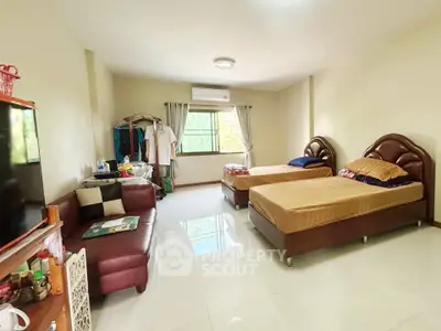 Spacious bedroom with twin beds, cozy sofa, and ample natural light.