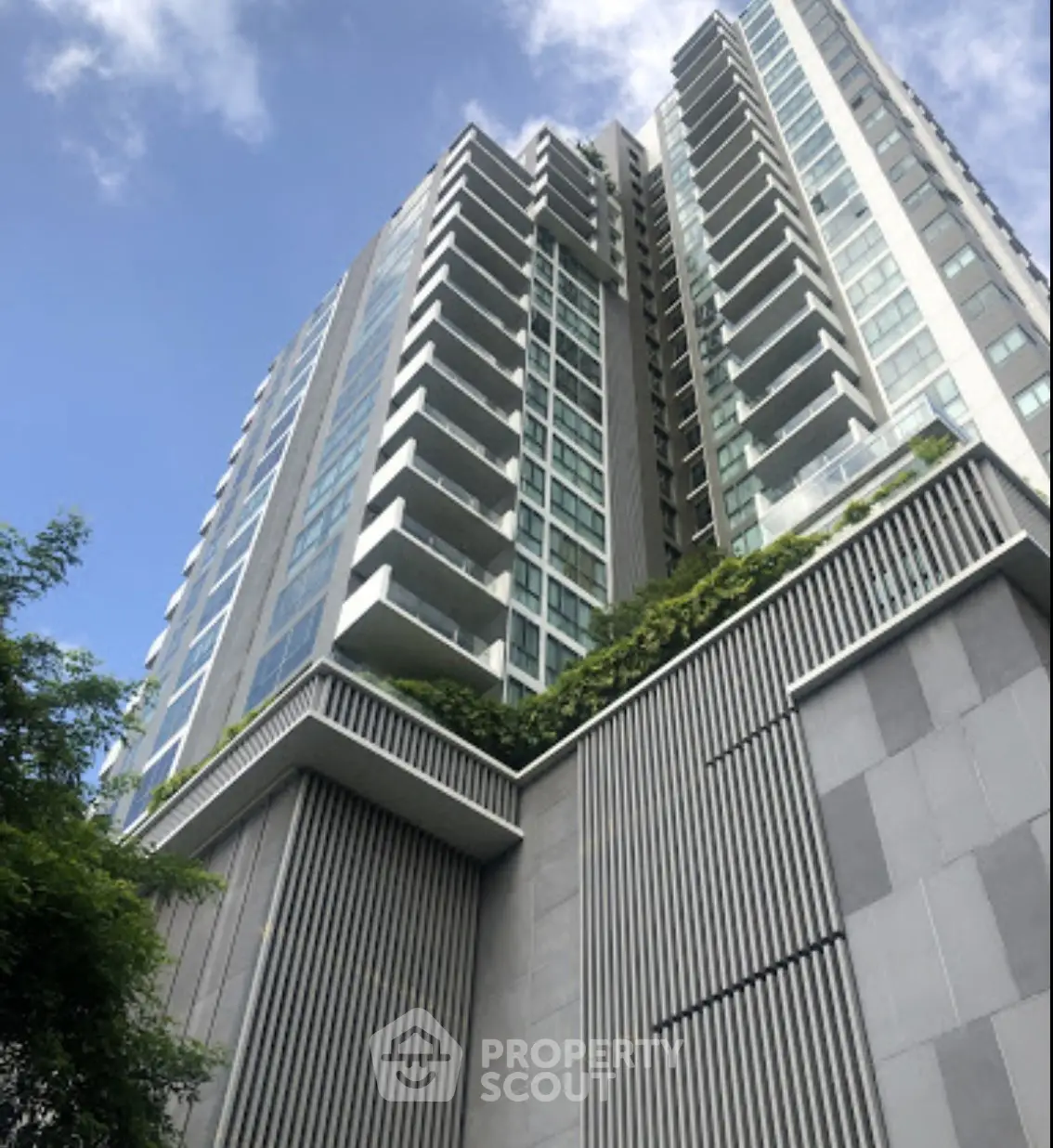 Modern high-rise building with sleek architecture and lush greenery, perfect for urban living.