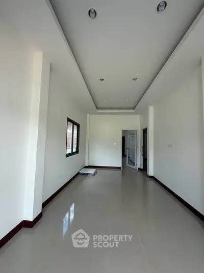 Spacious unfurnished room with modern ceiling lights and large window, perfect for customization.