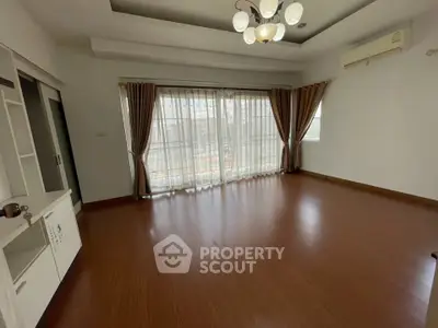 Spacious living room with wooden flooring and large windows for natural light.