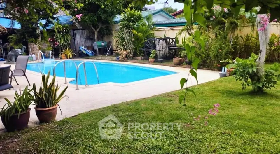 Charming backyard with inviting pool and lush garden, perfect for relaxation and outdoor gatherings.