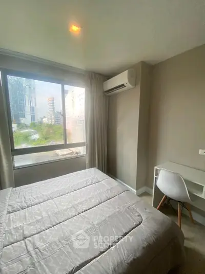 Cozy bedroom with large window and modern air conditioning unit, perfect for urban living.