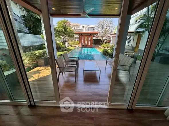 Luxurious poolside view from modern patio with sliding glass doors and lush garden.