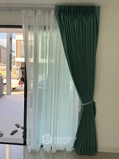 Modern interior with elegant green curtains and a view of the street, showcasing stylish living space.