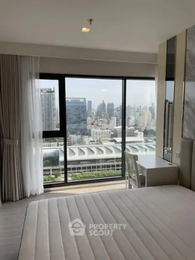 Modern bedroom with stunning city view through large windows, featuring a sleek design and ample natural light.