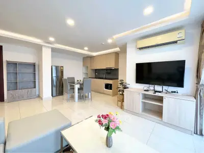 Modern open-layout living room with kitchen, featuring sleek furniture and bright lighting.