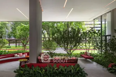 Luxurious modern lobby with lush greenery and stylish red seating, offering a serene and inviting atmosphere.