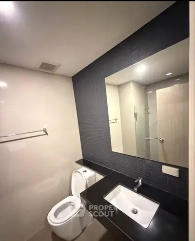 Modern bathroom with sleek fixtures and large mirror in contemporary apartment.