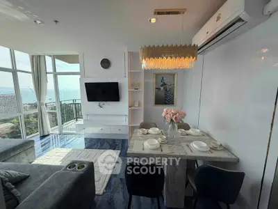 Luxurious living room with ocean view, elegant dining area, and modern decor in high-rise apartment.