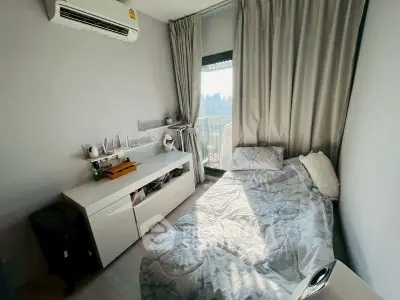 Cozy bedroom with natural light and city view, featuring modern air conditioning and sleek furniture.