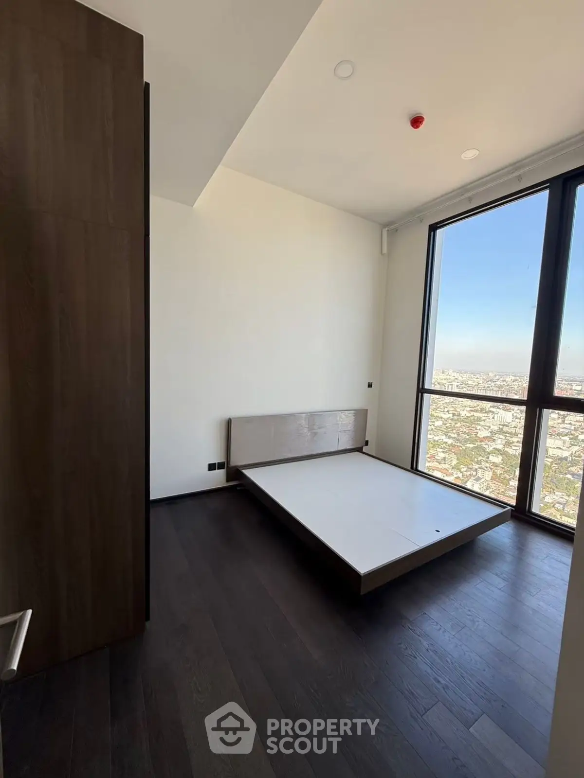 Modern bedroom with panoramic city view and sleek dark wood flooring.