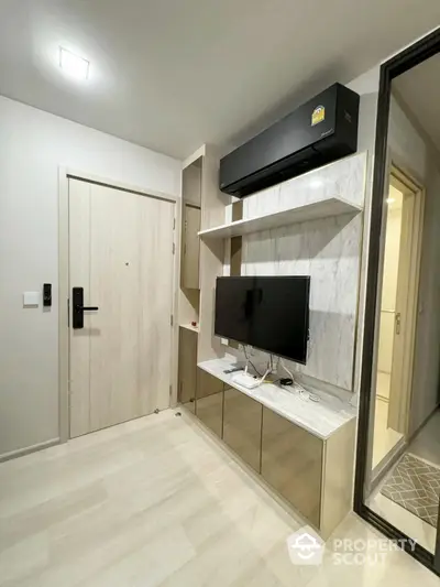 Modern apartment entrance with sleek storage and mounted TV