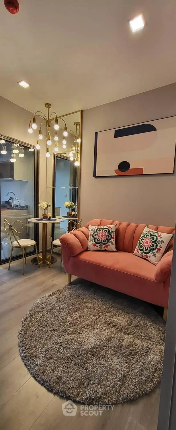 Chic living room with modern decor, featuring a plush pink sofa, stylish chandelier, and elegant dining area.