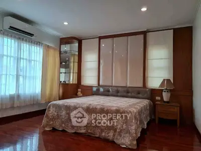 Spacious bedroom with elegant wooden flooring and large windows for natural light.