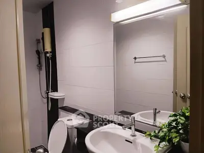 Modern bathroom with sleek fixtures and large mirror, featuring a shower and stylish sink.