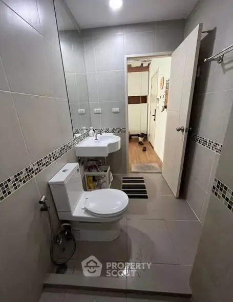 Modern bathroom with sleek fixtures and neutral tiles, featuring a stylish vanity and toilet.
