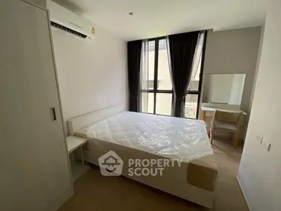 Modern bedroom with large window, natural light, and minimalist furniture in a stylish apartment.