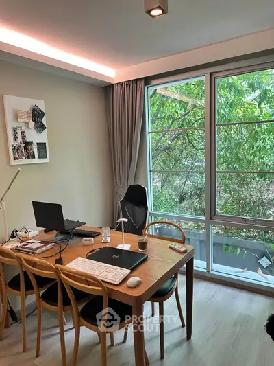 Modern study room with large window and garden view, featuring a wooden desk and chairs.