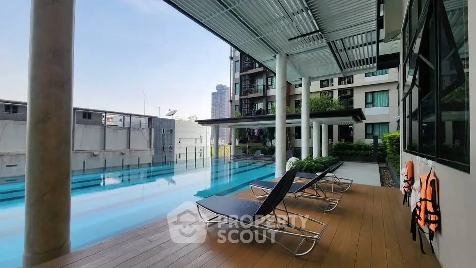 Luxurious apartment poolside with modern lounge chairs and city view, perfect for relaxation and leisure.