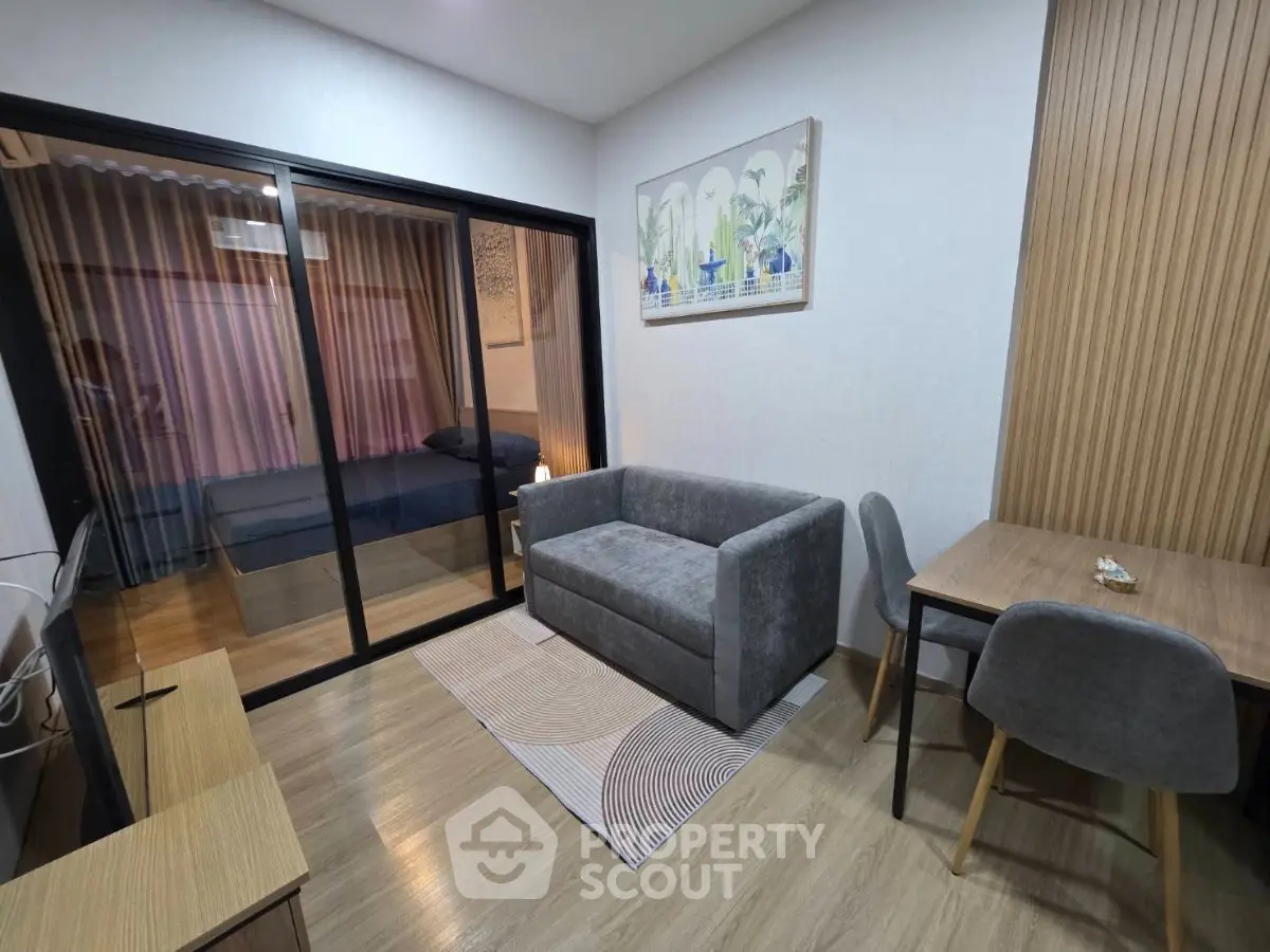 Modern living room with cozy sofa and dining area, featuring sliding glass doors to bedroom.