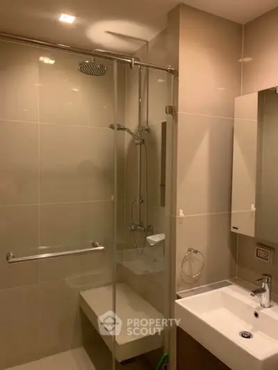 Modern bathroom with glass shower and sleek sink in contemporary apartment.