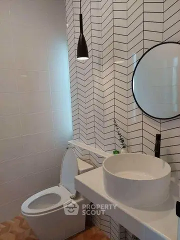 Modern bathroom with stylish herringbone tiles and round mirror