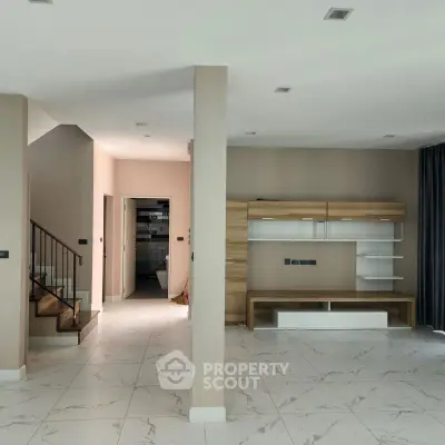 Spacious modern living room with elegant staircase and sleek storage unit.