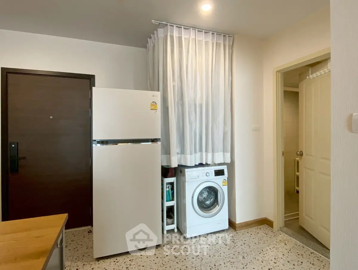 Compact utility area with fridge and washing machine in modern apartment