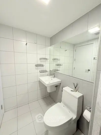 Modern bathroom with sleek white tiles and contemporary fixtures.