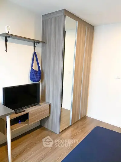 Modern bedroom with sleek wardrobe and compact TV setup