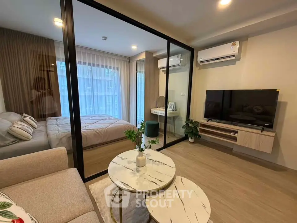Modern apartment interior with glass partition, cozy living area, and stylish bedroom.