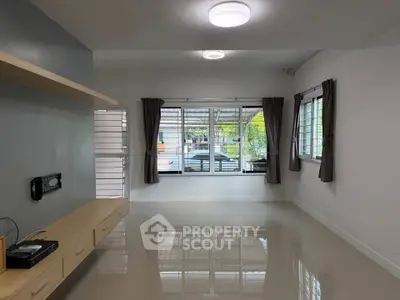 Spacious living room with large windows and modern lighting, perfect for family gatherings.