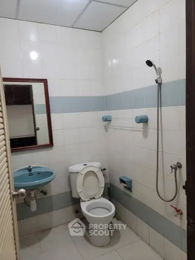 Compact bathroom with shower, toilet, and sink in tiled setting